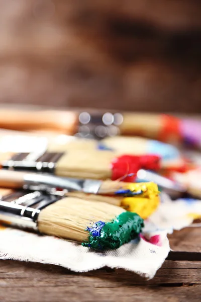 Brushes with colorful paints on old wooden background — Stock Photo, Image