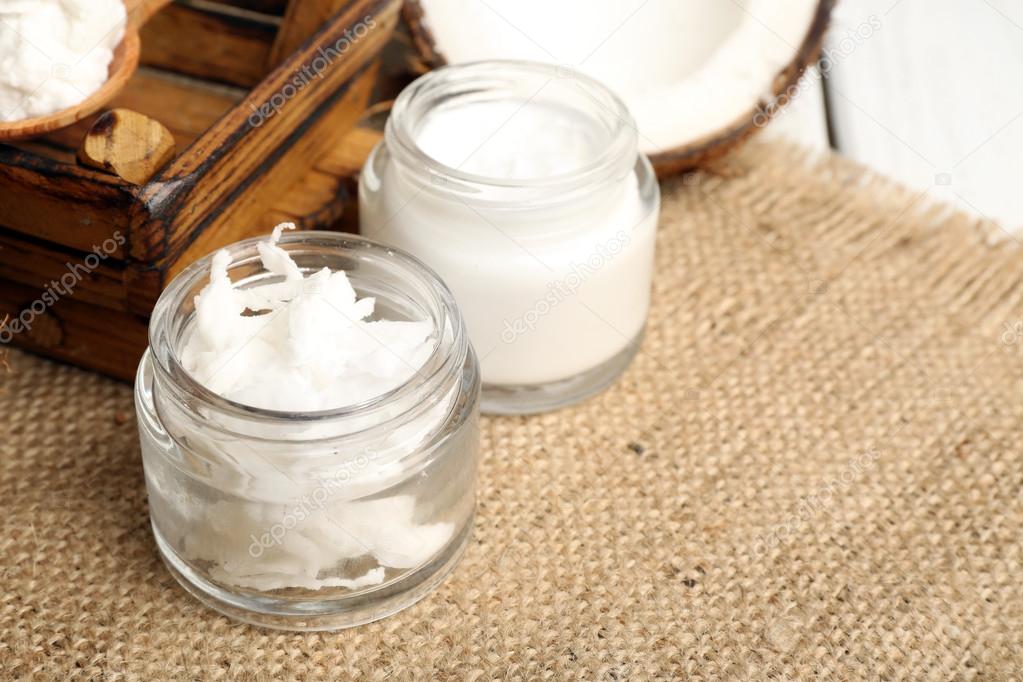 Coconut with jars of coconut oil and  cosmetic cream on sackcloth background
