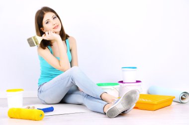 Güzel kız boyama duvar için ekipman ile katta oturan