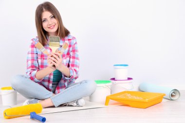 Güzel kız boyama duvar için ekipman ile katta oturan