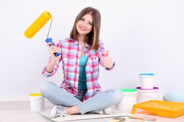 Güzel kız boyama duvar için ekipman ile katta oturan