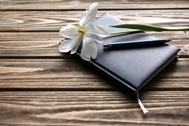 Defter ile ahşap arka plan üzerinde kalem ve Beyaz Lale