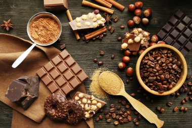 Still life with set of chocolate, nuts and spices on wooden table, top view clipart