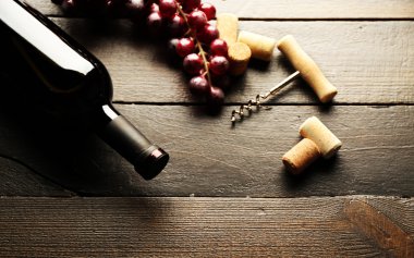 Cam şişe şarap mantarlar ve ahşap masa arka plan üzerinde üzüm ile