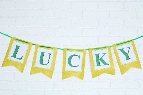 Word Lucky written on paper flags on brick wall background — Stock Photo, Image