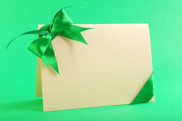 Card decorated with bow on green background — Stock Photo, Image