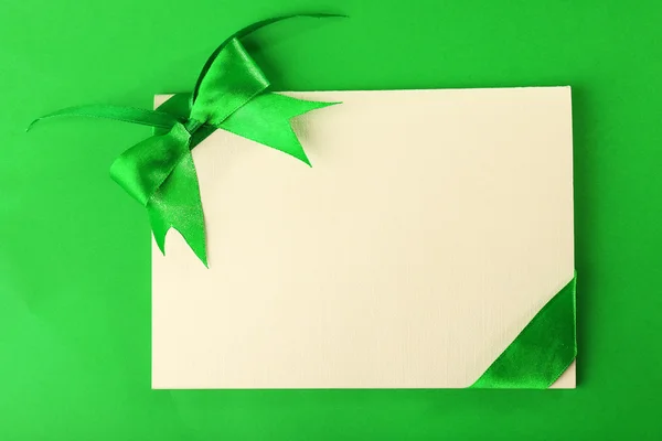 Картка прикрашена бантом на зеленому фоні — стокове фото