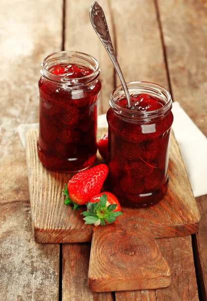 Frascos de mermelada de fresa con bayas sobre fondo de madera — Foto de Stock