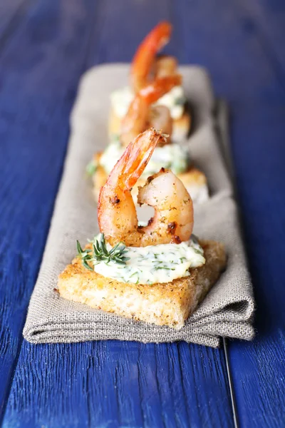 Appetizer canape with shrimp on napkin on table close up — Stock Photo, Image