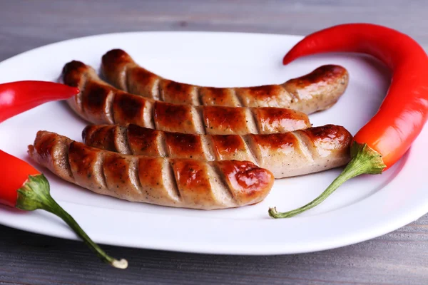 Grilované párky na desce s chilli papričkou na stole zblízka — Stock fotografie