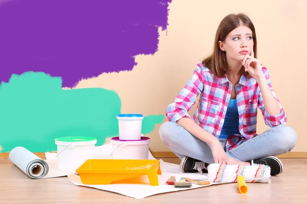 Menina bonita sentada no chão com equipamento para pintura de parede — Fotografia de Stock