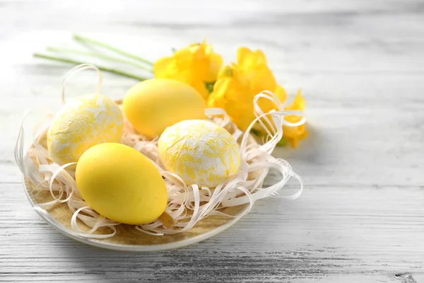 Composición de Pascua con huevos coloridos en plato sobre fondo de mesa de madera —  Fotos de Stock