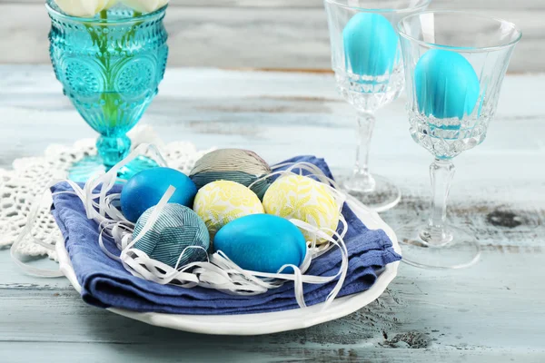 Osterkomposition mit bunten Eiern auf Serviette auf hölzernem Tischhintergrund — Stockfoto