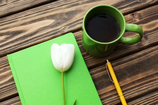 Notebook s šálkem čaje a bílý Tulipán na dřevěné pozadí — Stock fotografie