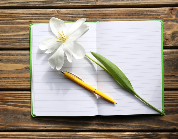 Notizbuch mit Stift und weißer Tulpe auf Holzgrund — Stockfoto