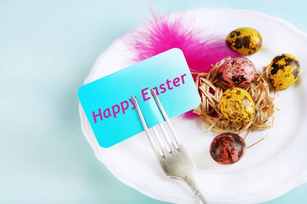 Ajuste de mesa de Pascua con tarjeta y huevos de Pascua sobre fondo de madera color — Foto de Stock