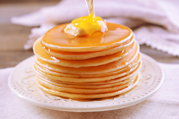 Delicious pancakes with honey on plate on table close-up