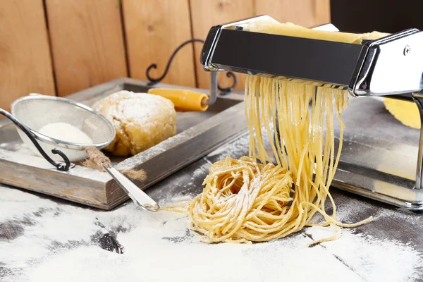 Hacer vermicelli con máquina de pasta y harina espolvoreada sobre fondo de madera —  Fotos de Stock