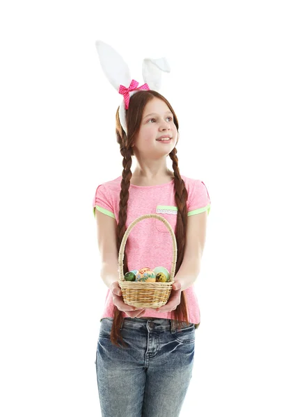 Mooi meisje dragen Easter bunny oren en houden rieten mand met Pasen eieren, geïsoleerd op wit — Stockfoto