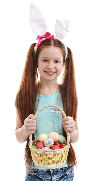Красивая маленькая девочка с пасхальными кроличьими ушами и плетеной корзиной с пасхальными яйцами, изолированными на белом — стоковое фото