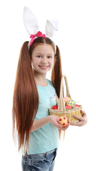 Beautiful little girl wearing Easter bunny ears and holding wicker basket with Easter eggs, isolated on white — Stock Photo, Image