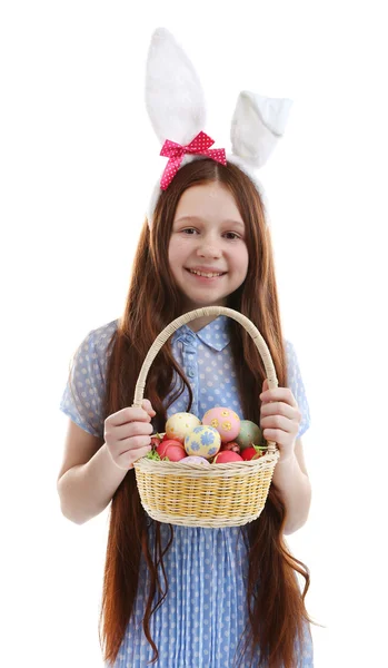 Schönes kleines Mädchen mit Osterhasenohren und Weidenkorb mit Ostereiern, isoliert auf weiß — Stockfoto