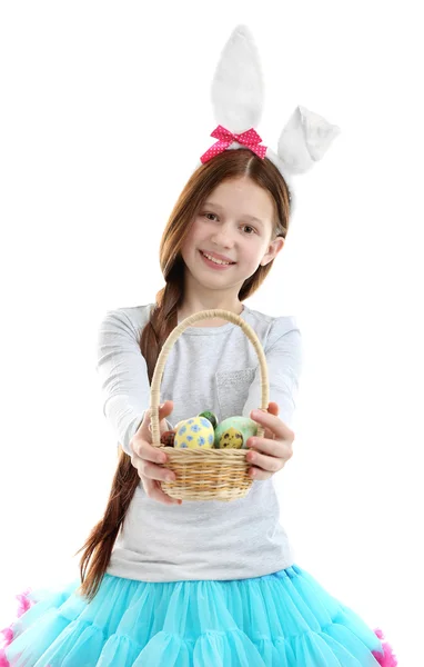 Bella bambina indossa orecchie coniglietto di Pasqua e tenendo cesto di vimini con uova di Pasqua, isolato su bianco — Foto Stock