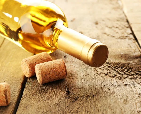 Glass bottle of wine with corks on wooden table background — Stock Photo, Image