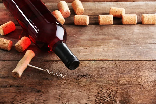 Szklana butelka wina z korki i korkociąg na drewnianym stole tło — Zdjęcie stockowe