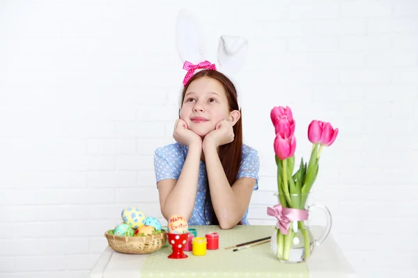 Jolie fille décore oeufs de Pâques, sur fond clair — Photo