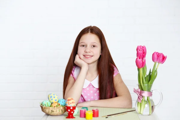 Söt flicka dekorerar påskägg, på ljus bakgrund — Stockfoto