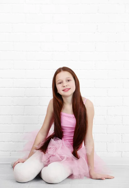 Beautiful little ballerina on  white bricks wall background — Stock Photo, Image