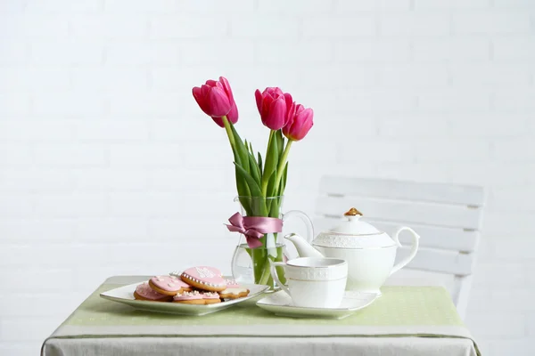 Teservis med blommor på bordet, på ljus bakgrund — Stockfoto