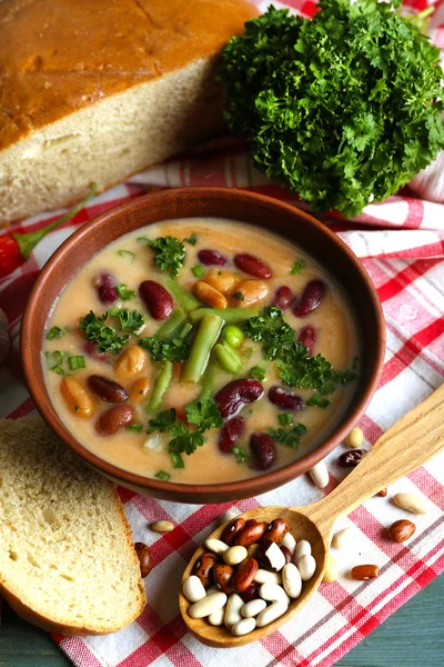 Sopa de frijol en tazón con pan fresco en rodajas en servilleta, sobre fondo de mesa de madera —  Fotos de Stock