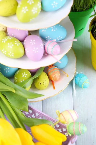 Пасхальные яйца на вазе и тюльпаны на столе крупным планом — стоковое фото