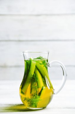 Ahşap masa üzerinde taze organik salatalık suyu ile cam ibrik