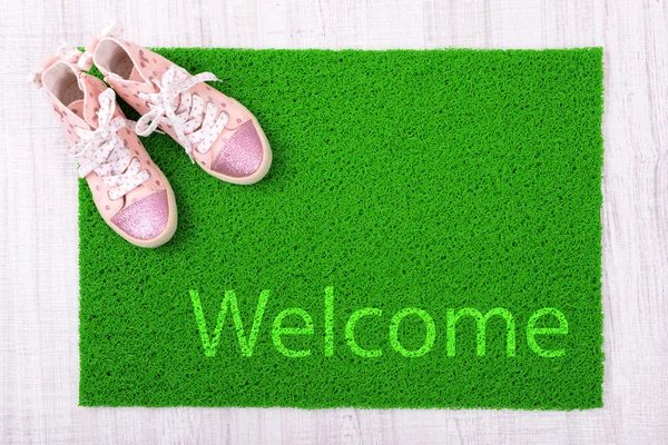 Sneakers and green carpet on floor — Stock Photo, Image