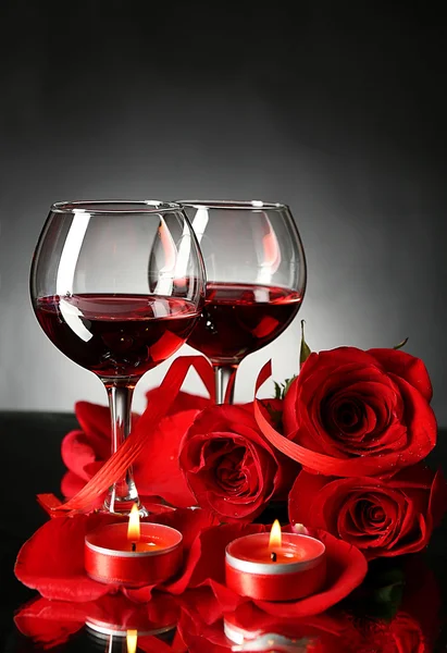 Sammansättning med rött vin i glasen, röd ros och dekorativt hjärta på mörk bakgrund — Stockfoto