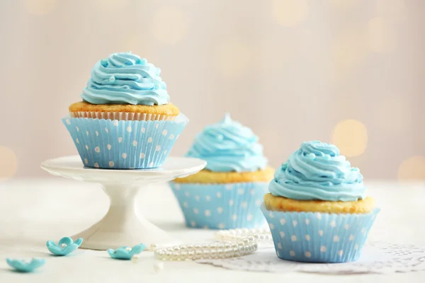 Deliciosos cupcakes na mesa no fundo claro — Fotografia de Stock