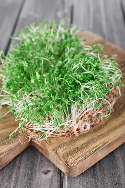 Fresh cress salad on cutting board and wooden planks background — Stock Photo, Image