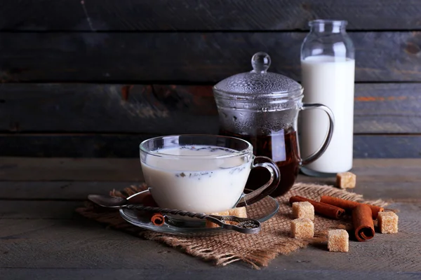 Musta tee maidolla lasitavaroissa ja kertakäyttöisellä sokerilla värilaudoilla tausta — kuvapankkivalokuva