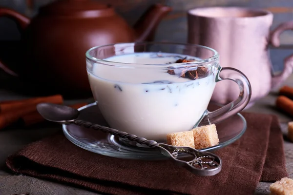 Black tea with milk in cups and teapot with lump sugar on color wooden planks background — Stock Photo, Image