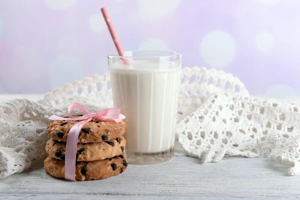 Tasty cookies and glass of milk on color wooden table, on bright background — Stock Photo, Image