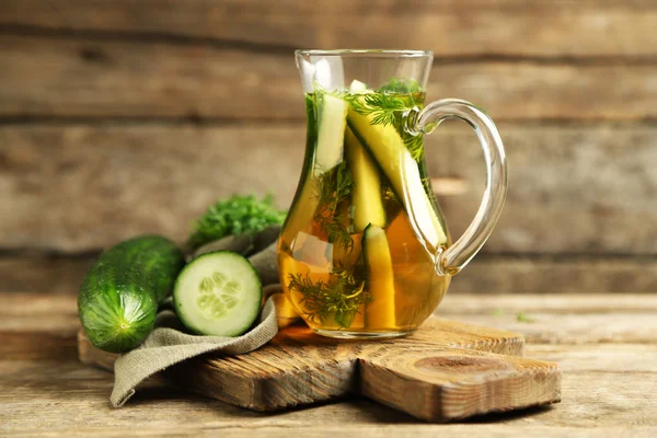 Glass ewer with fresh organic cucumber water on wooden table — Stock Photo, Image