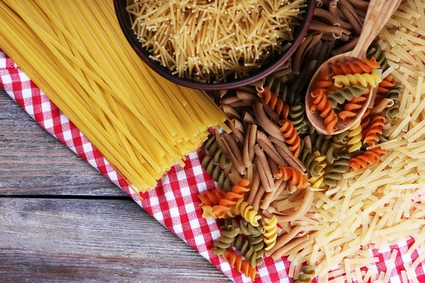 Diferentes tipos de pasta en servilleta sobre fondo de madera —  Fotos de Stock