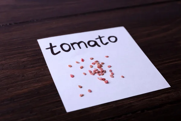 Kağıt ahşap arka plan üzerinde domates tohumları — Stok fotoğraf