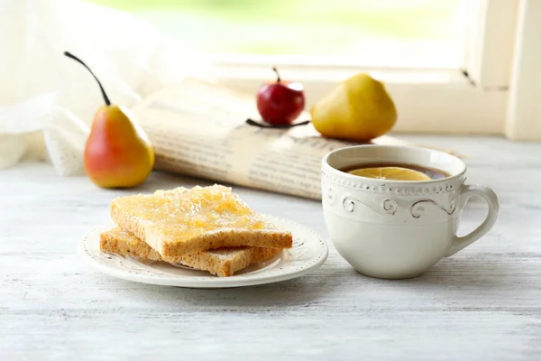 Toasts with honey on plate with cup of tea on light background — Stock Photo, Image