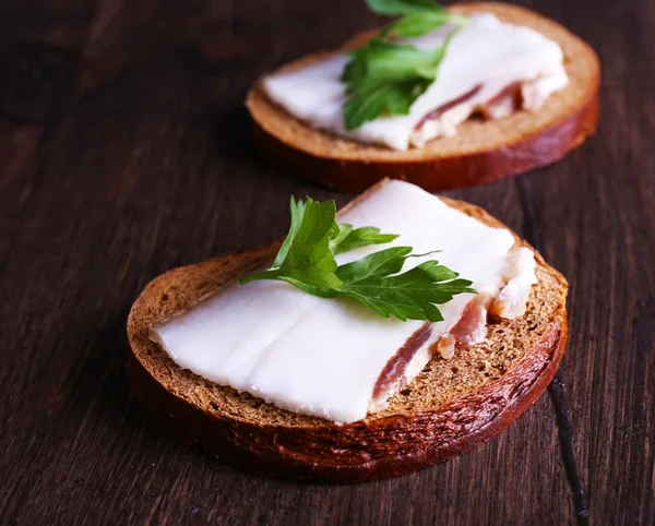 Сэндвичи с салом и петрушкой на деревянном фоне — стоковое фото