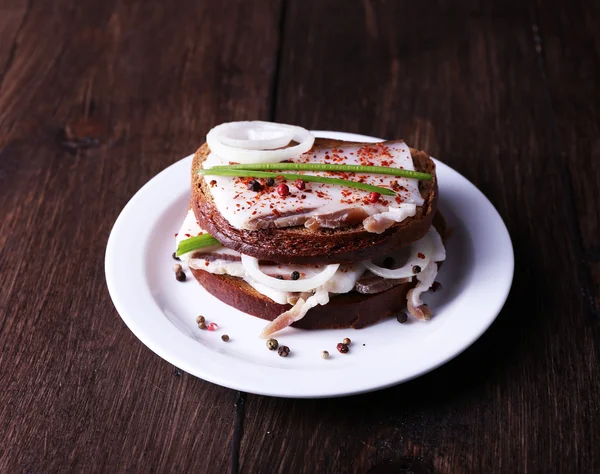 Sandwiches with lard and onion on plate on wooden background — Stock Photo, Image