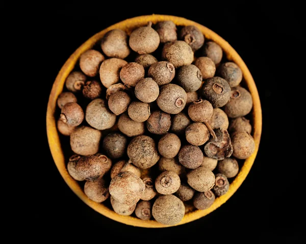 Allspice in wooden bowl, isolated on black — Stock Photo, Image